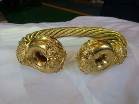 The Snettisham Great torc - a gold, c-shaped, neck ring with doughnut shaped terminals (ends) and twisted wire for the neck ring. The neck ring is made from 64 wires.
