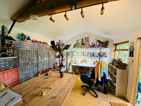 My LEGO shed. There are lots and lots of plastic boxes with labels for each type of LEGO piece. At one end of the shed is a table with studio lights where I film my builds. There are shelves on which are lots of LEGO buildings.