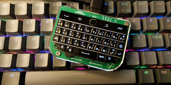 a small blackberry keyboard mounted on a pcb from solderparty. It lies on a normal size keyboard with rainbow backlight for reference. It,s tiny!