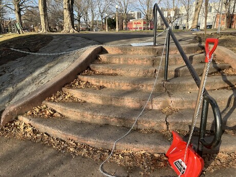 A red plastic snow shovel is chained to the bottom of the stairs with a long chain to permit shovelling of the entire area.