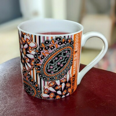 A white bone china mug, covered with squiggly orange, pink and black designs that turn out to be an artist's representation of the Influenza virus magnified by 680,000 times.