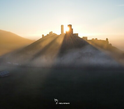 The rising sun sparkles through the 1000 year old ruins of Corfe Castle on a misty morning