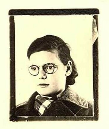 A portrait photograph of a girl wearing glasses. She is wearing a coat and has dark hair.