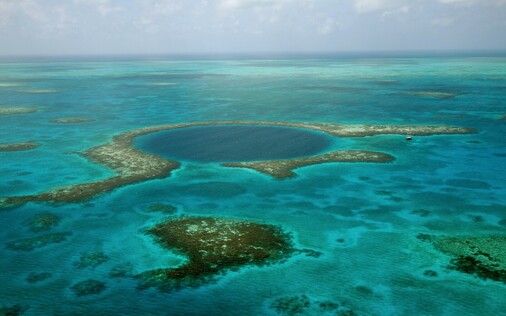 A blue hole in Belize - it's a giant sink hole off the coast where sand collects. A sailboat anchored nearby looks tiny in comparison.