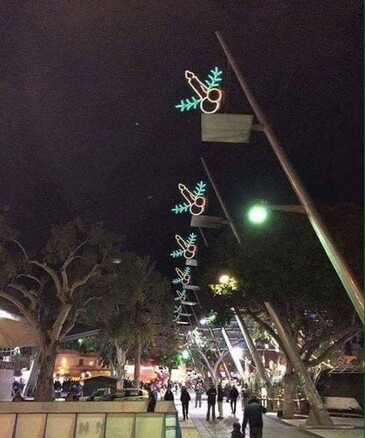 Decorations on a downtown street of light up candles over holly berries that make an unintended phallic shape.