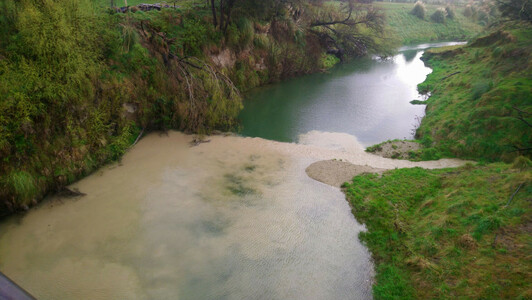 Waimatā River in Gisborne, Aotearoa New Zealand following a sudden rain event. Sediment laden water from a small tributary draining from a farm is entering the main river. Main river is much cleaner and the small tributary water is creating a large sediment plume as a result