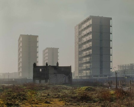 3 high-rises in mist behind a derelict Victorian house on a wasteland in the foreground