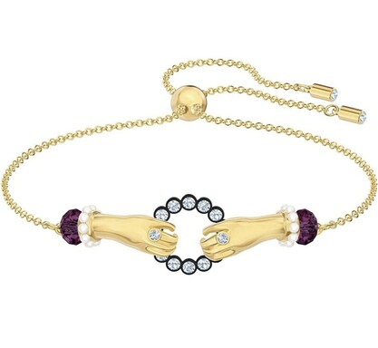 a gold bracelet with two ringed hands clasping either side of a large crystal circle