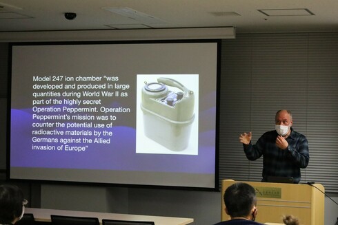 Shot of Bo Jacobs giving a lecture with a slide beside him