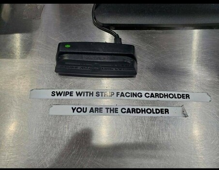 A card reader with two printed labels glued on: swipe with strip facing cardholder + you are the cardholder
