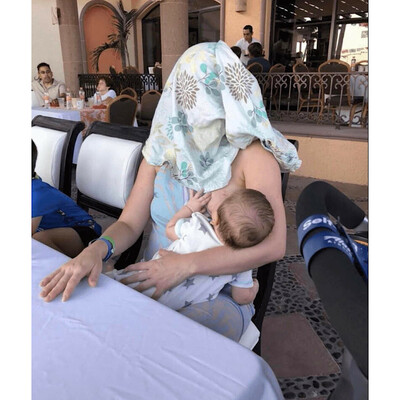 Woman nursing her child while covering her own head.