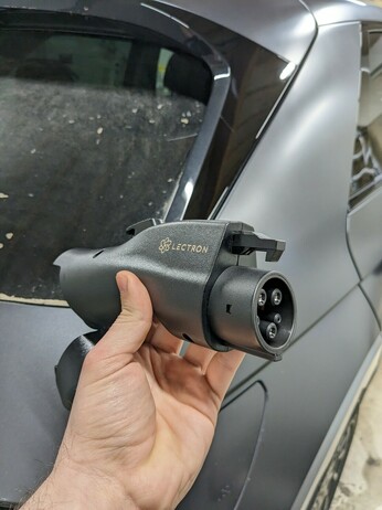 The adapter in my hand, revealing lectron branding and the male j1772 connector on the right