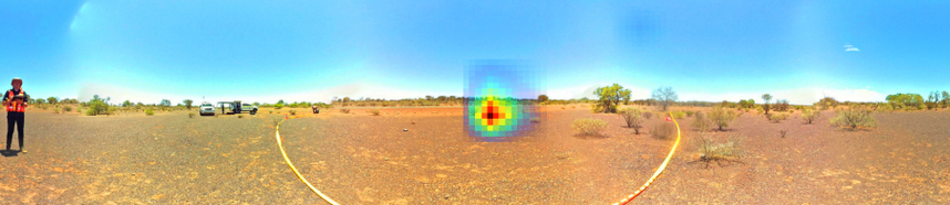 Panoramic image off a piece of Australian desert. The area at the centre of the image is cordoned off. Overlaid on the image is a red heatmap blob, clearly showing the gamma rays coming from the radioactive source, which isn't visible.