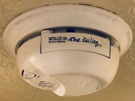 A mounted smoke alarm with a label reading “installed on” followed by a handwritten “the ceiling.”