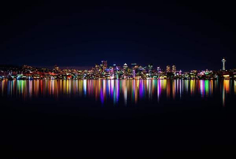 Seattle, Washington at night, with the lights reflecting off the waters of the Puget Sound