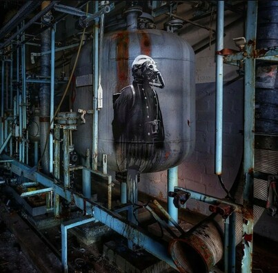 Streetartwall. In an abandoned building, a ghostly figure in a black coat and a gas mask is sprayed / painted on a large, gray metal cauldron. The environment consists of blue tubes and
superstructures.
Info: The artist usually works in hidden places and with photographers, which give his murals a special, usually gloomy, aura.