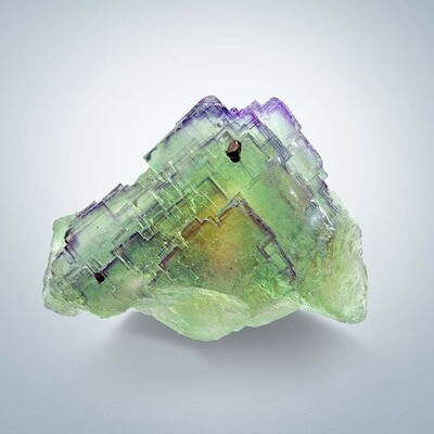 Triangular green fluorite specimen, with a yellow patch in the center and purple along the edges of each crystal.