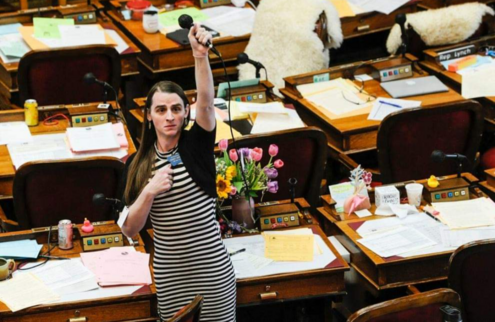 Rep. Zoey Zephyr, on the Montana house floor, raising her mic (which was shut off) above her head.