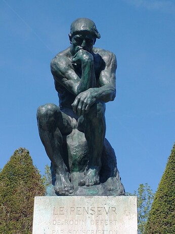 Rodin's The Thinker fills the screen with blue sky