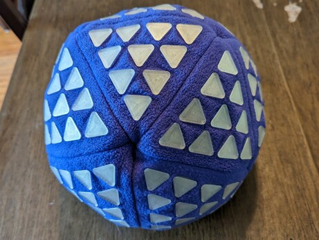 An icosahedron sewn from purple fleece that is about 16 inches in diameter and has a triangular grid of ten 3D printed triangles which covering each side.