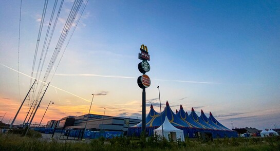 A picture at sunset showing the huge Hoogvliet commercial bakery & bread distribution centre on the industrial estate in Bleiswijk, at the junction of the A12 & N209. There is a cluster of fast food restaurants & petrol stations there which always seem to be busy for some reason – there a big advertising sign for KFC, McDonalds, Starbucks, & Burger King. There is a big circus-type tent being erected in front of the Hoogvliet bakery, although whether it’s for an actual circus or another event, I have no idea. Also visible in the picture are high tension power lines of the new 380kV network which spans this part of Zuid-Holland. There is a substation nearby, possibly to feed the bakery. There are also some airplane contrails visible. All in all, it adds up to a snapshot of modern civilisation consuming energy to produce crappy food & fly willy nilly around the world, killing us with climate change. And yet just like the Romans, as long as we have bread & circuses, we remain docile.