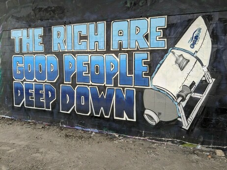Mural on a black wall featuring the titan submersible and the words "The rich are good people deep down" in blue