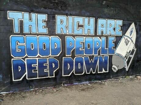 Mural on a black wall featuring the titan submersible and the words "The rich are good people deep down" in blue
