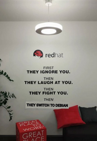 A photo from the Red Hat office, with a wall mural saying "first they ignore you. then they laugh at you. then they fight you. then they switch to Debian", with the last line being photoshopped in crudely.