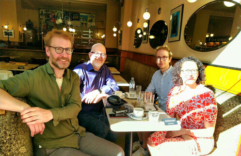 Photograph of Geoff Bird, Michael Symmons Roberts, Timo Frühwirth, and Sandra Mayer sitting at a table in a Viennese café.