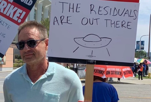 David Duchovny stood in front of a hand drawn picket sign

"the residuals are out there"

And a picture of a UFO 🛸