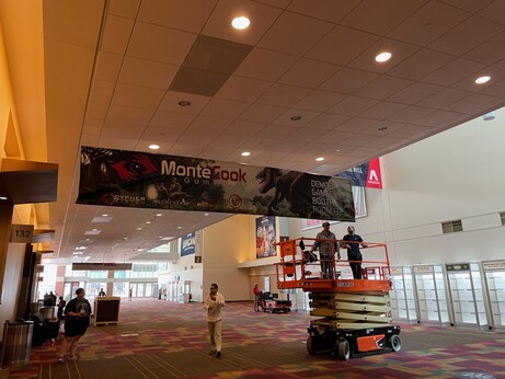 The Monte Cook Games Room 132 sign being put up at Gen Con, 2023