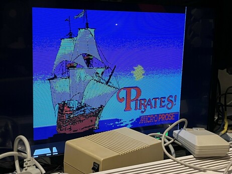 The title screen for Sid Meier’s Pirates on the NEC PC8801-MC.  It has a ship against a blue sky with Pirates! Written in red and the Microprose logo, also in red, beneath it