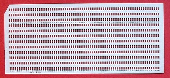 An IBM punchcard with all of its holes punched, leaving row after row of rectangular holes.