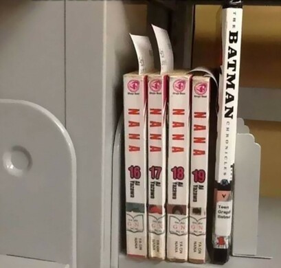 A group of books lined up on a shelf so that the titles spell out Nana, Nana, Nana, Nana, Batman.