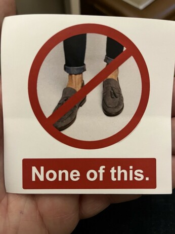 Sticker was text saying “none of this” and an image of a man’s sockless feet in a pair of tassled loafers shoes.