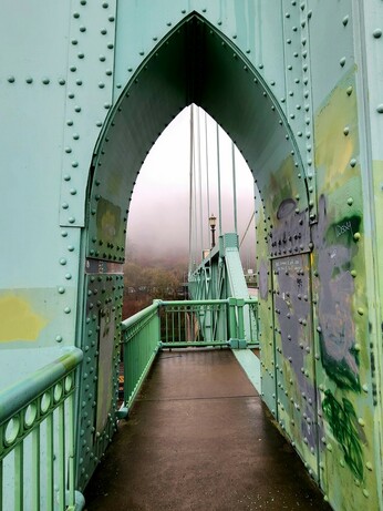 Close up of an opening in one of the towers that the pedestrian walkway passes through. It's also in the shape of a pointed gothic arch. There are patches of paint where graffiti has been covered up.