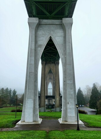Beneath the bridge where the pylons echo the same gothic arch shape, which is what gives Cathedral Park it's name. This view is head on showing several pylons in the distance through the opening of the nearest one.