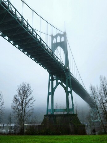 The bridge seen from below, showing a full view of one of the towers. The roadway passes día diagonally through the frame from upper left to lower right.