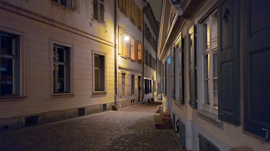 alte strassenlaterne an einer historischen hausfassade am rheinsprung, deren licht auf das nächtliche kopfsteinpflaster und die häuser an der gasse fällt