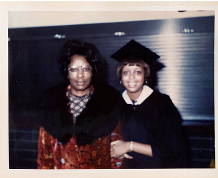 Photo of my mother and her mother, two Black women. My mother wears a black graduation cap and gown. My grandmother wears a floral coat with large black fur collar.