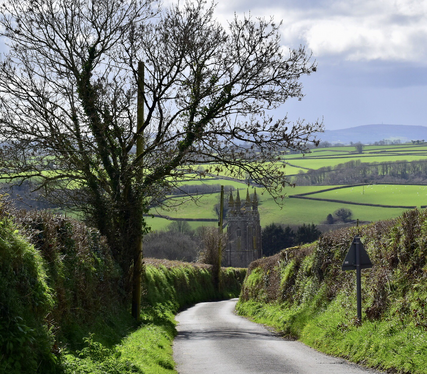 A country lane leads to a .Church tower