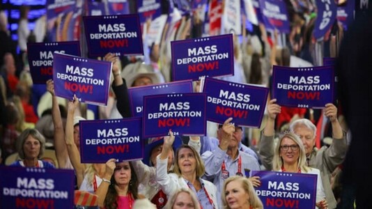 Republicans at the RNC holding “Mass Deportation Now!” signs
