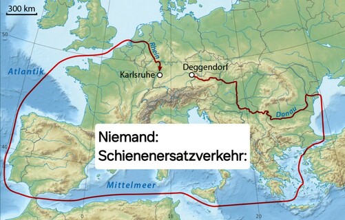 Ein humoristisches Bild welches die europäische Landkarte zeigt, darauf eingezeichnet sind Deggendorf und Karlsruhe welche mit einer roten Linie verbunden sind. Diese rote Linie geht jedoch nicht im direktesten Sinne zwischen die beiden Städte, sondern nimmt den größten Umweg, über den Ozean, zwischen Kontinenten und um Länder drumherum. In der Mitte steht geschrieben „Niemand: Schienenersatzverkehr:”