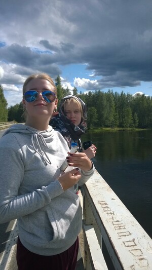 My step daughters are standing on a bridge. The younger one is maybe 22 and she wears a hoodie and sunglasses. The older one is maybe 27 at that time and she has a scarf around her head because she is afraid of horseflies.