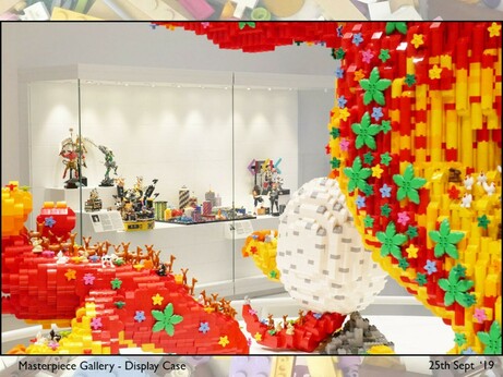 Long view of the display case framed by bright red yellow and green parts of the Technic Dinosaur which is also in the Masterpiece Gallery