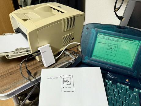 A Newton eMate 300, an AsanteTalk. And a laser printer. There is a crudely drawn picture on a printout and the newton display
