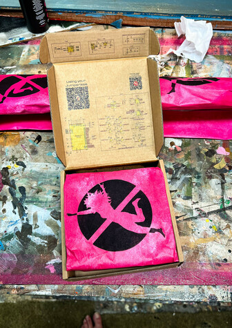 An OG jumperless box with pink stenciled paper as packing material