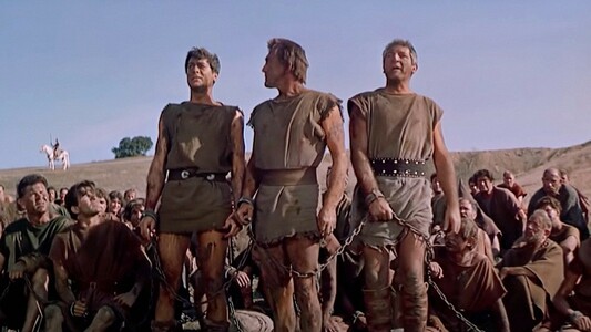 Color photo from 1960 Stanley Kubrick film, "Spartacus."
(Standing L to R) Tony Curtis, Kirk Douglas, and another actor having defied the might of Rome as part of a slave army, claim to be Spartacus to save their leader.