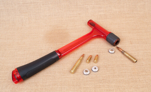 An unloading hammer by hornady with the caliber shims and some ammo, showvasing how it's being used to disassemble ammunition by knocking the projectile out of it.