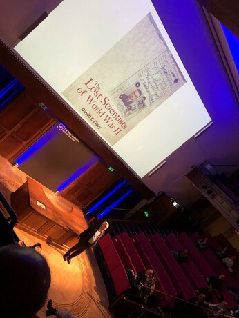 David Clary at the start of his talk with the cover of his book visible behind.